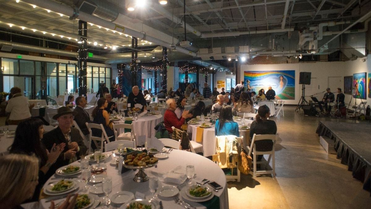 McNichols Building interior, people seated at rounds, with stage and band 1200x675